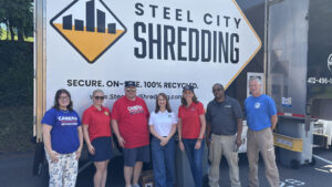 Sen. Bartolotta poses with a group of people next to an industrial shredder truck.